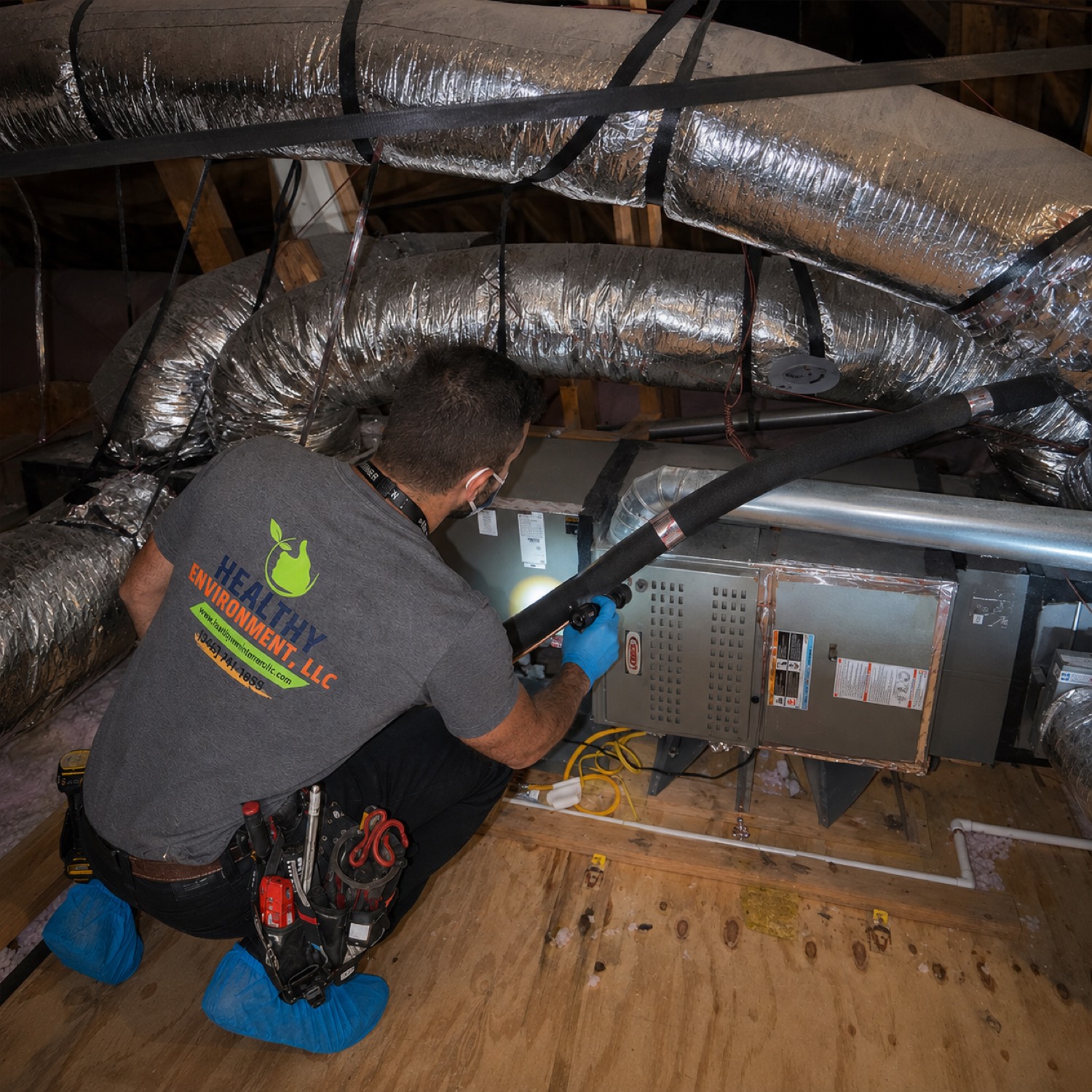 Technician performing air duct cleaning on an HVAC system in a Sugar Land attic